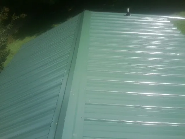 New green metal panels meeting at the ridge of a roof — Flat Roof Repair work by our crew in Steeles Tavern