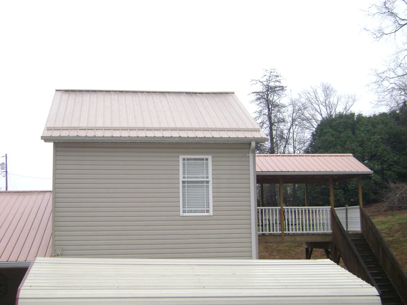 Tan metal roofs on a two story addition and attached porch, from a Roof Replacement job in Steeles Tavern